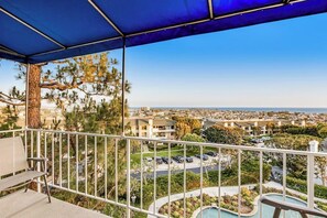 Ein Balkon mit Blick auf eine Stadtlandschaft, einen Pool und einen Baum.
