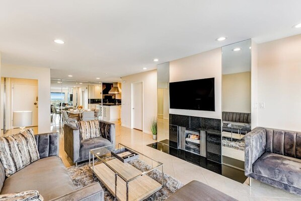 A modern living room with a sofa, coffee table, and fireplace. - Ocean-view condo, balcony, clubhouse, gym, pool, hot tub, snowbird haven (Newport Beach)