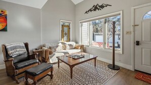 Ein Wohnzimmer mit Sofa, Sessel, Couchtisch und einem großen Fenster.
