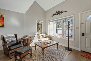 Ein Wohnzimmer mit Sofa, Sessel, Couchtisch und einem großen Fenster.