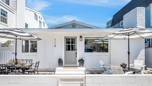 A white building with a number '8' on the door, outdoor seating with umbrellas, and a small patio area.
