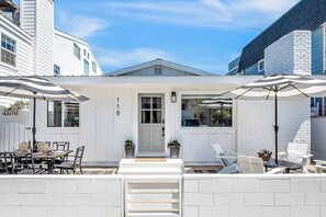 Ein weißes Gebäude mit der Nummer 8 an der Tür, Außenbereich mit Sonnenschirmen und eine kleine Terrasse.