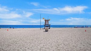 A lifeguard tower on a sandy beach with the ocean in the background.