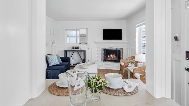 A white interior with a fireplace, a sofa, and a table with a pitcher and bowl.