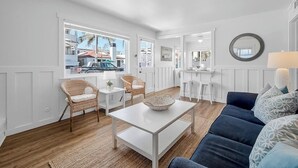 A spacious living area with a sofa, chairs, a coffee table, and a kitchen in the background.