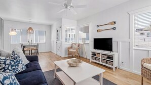 Un salon moderne comprenant un canapé, une table basse, un téléviseur et un coin repas avec des chaises et une table.