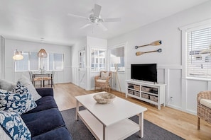 Un salon moderne comprenant un canapé, une table basse, un téléviseur et un coin repas avec des chaises et une table.