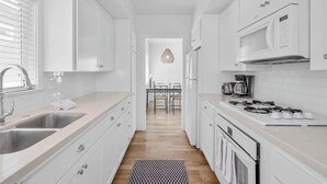 Une cuisine moderne avec des meubles blancs, des appareils en acier inoxydable et un plancher en bois.