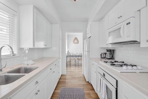 Une cuisine moderne avec des meubles blancs, des appareils en acier inoxydable et un plancher en bois.