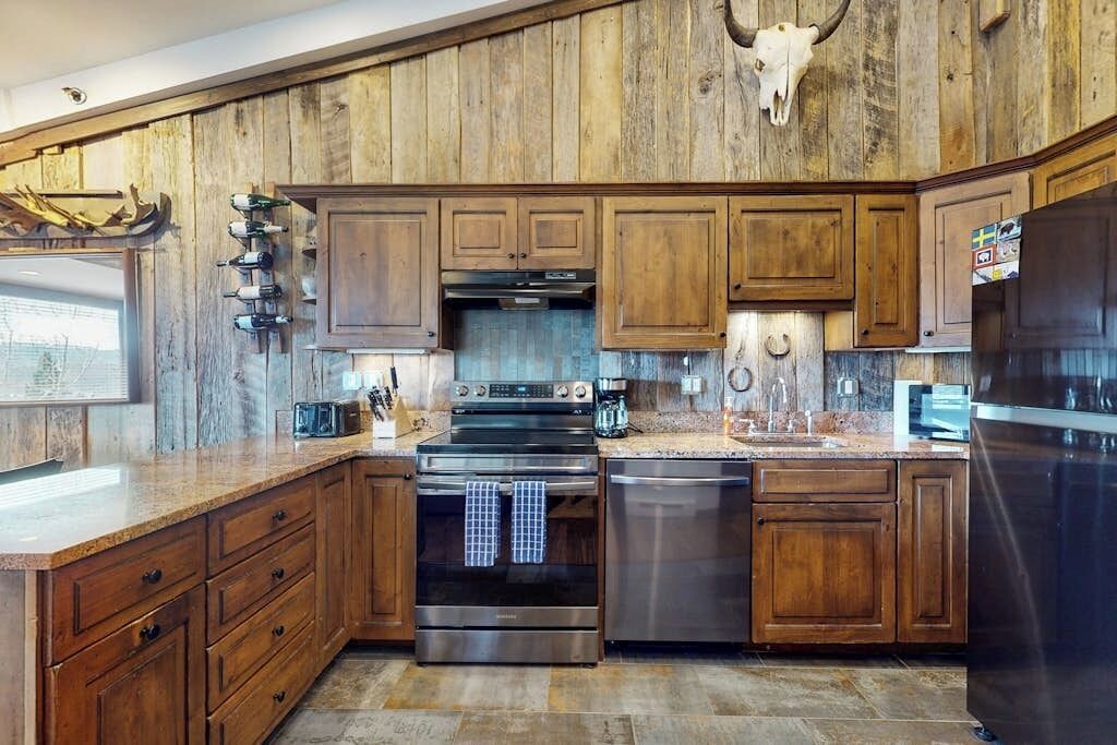 Una cocina con armarios de madera, electrodomésticos de acero inoxidable y un cráneo de vaca montado.