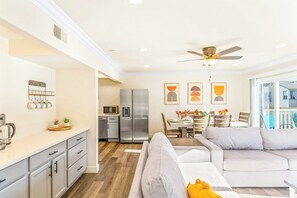 Eine moderne Küche mit Essbereich, grauen Sofas und einem Deckenventilator.