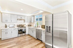 Une cuisine moderne avec des meubles blancs, des appareils en acier inoxydable et un plancher en bois.