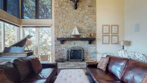 A living room with a stone fireplace, leather sofas, and a piano. - Upscale home with lake views, gas grill, washer/dryer, fireplace, patio, deck (Lake Arrowhead)