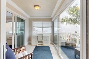 Ein Balkon mit Schreibtisch, Stühlen und Meerblick.