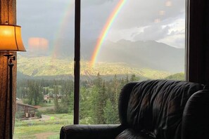 Ein Zimmer mit Blick auf eine Berglandschaft und einen Regenbogen.