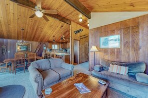 Ein rustikales Interieur mit Holzwänden, einem Essbereich und zwei Sofas.