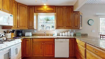 A kitchen with wooden cabinets, a microwave, a stove, a dishwasher, and a window with a view of the outside.