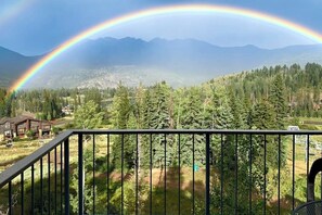 Eine Berglandschaft mit Regenbogen, einer Holzhütte und bewaldetem Gebiet.