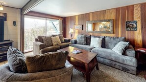 Ein gemütliches Wohnzimmer mit Kamin, zwei Sofas, einem Couchtisch und einem großen Spiegel an der Wand.