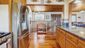 Eine Küche mit Holzausstattung, einem Edelstahlkühlschrank, einem Holzessttisch und einer Treppe zu einer weiteren Ebene.