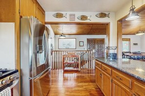 Eine Küche mit Holzausstattung, einem Edelstahlkühlschrank, einem Holzessttisch und einer Treppe zu einer weiteren Ebene.