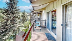 A balcony with a wooden deck, a chair, and a table. - Spacious condo with fireplace & balcony (Snowmass Village)