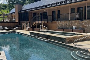 A swimming pool with lounge chairs, a staircase, and a building with a stone facade. - Spacious condo with fireplace & balcony (Snowmass Village)