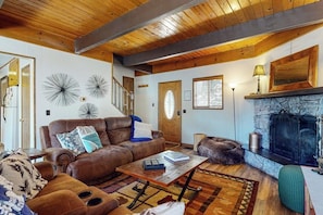 Un salon chaleureux avec une cheminée, un canapé en cuir et un plafond en bois.