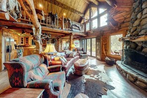 A log cabin interior with a fireplace, leather furniture, and a stone wall. - Spectacular mountain cabin with great views, deck, & fireplace - dogs OK (Durango)