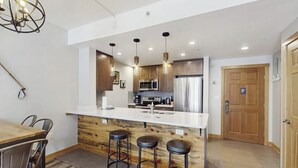 Een moderne keuken met een centraal eiland, barstoelen en roestvrijstalen apparatuur.
