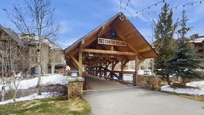 Een houten overdekte brug met de tekst 'Center Village', geflankeerd door stenen muren.