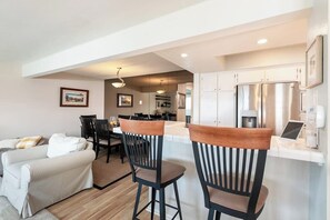 A modern kitchen with stainless steel appliances, a dining area with a white table and chairs, and a living area with a sofa and a coffee table. - Spacious Home w/ Fenced Patio, Grill & Balcony - 1 Mile to Beach & Pier Ave (Hermosa Beach)