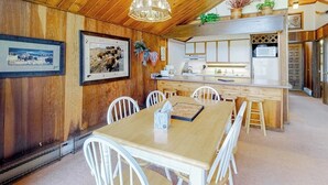A wooden interior with a dining table, chairs, a kitchen area, and framed pictures on the wall. - Ski-in/ski-out condo with on-site spa, balcony, fireplace & lake views (Durango)