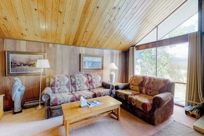 A cozy living room with wooden ceiling, two patterned sofas, a coffee table, and framed pictures on the wall. - Ski-in/ski-out condo with on-site spa, balcony, fireplace & lake views (Durango)