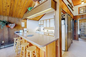 A kitchen with wooden cabinets, a central island with stools, a refrigerator, and a clock on the wall. - Ski-in/ski-out condo with on-site spa, balcony, fireplace & lake views (Durango)