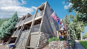 Un immeuble à plusieurs étages doté d’un balcon, d’un mur en pierre et de drapeaux.