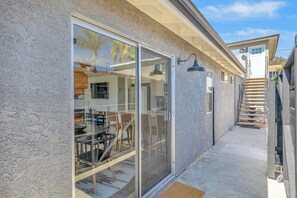 A house with a patio area, a sliding glass door leading to a dining room, and a staircase. - Dog-friendly duplex with washer/dryer, two full kitchens, & large backyard (San Clemente)