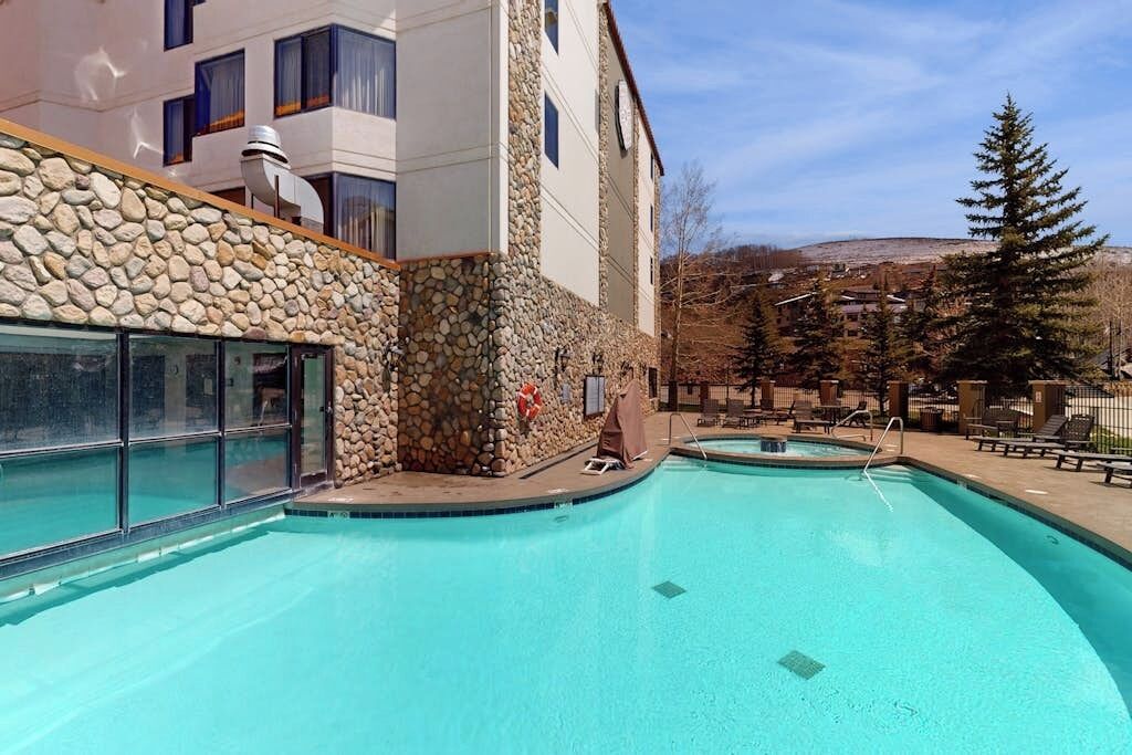 Un espace piscine agrémenté de murs en pierre, d’un coin salon abrité et offrant une vue sur une montagne.