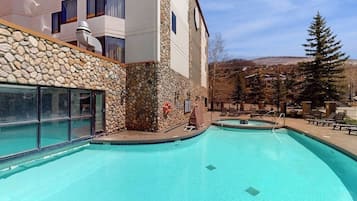 Un espace piscine agrémenté de murs en pierre, d’un coin salon abrité et offrant une vue sur une montagne.
