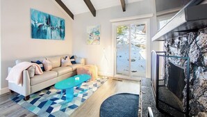 A living room with a sofa, coffee table, and artwork on the wall. - Colorful home with washer/dryer, AC & wood-burning fireplace in a lovely setting (Lake Arrowhead)
