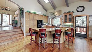 A spacious kitchen with a large island, wooden cabinets, and a view to the outside. - Beautiful home W/ Lake Access, Decks, Fire pit, Papoose Lake views, & EV Charger (Lake Arrowhead)