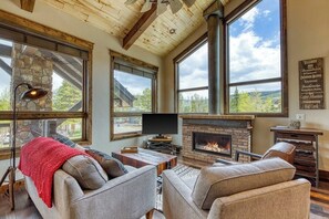 A spacious living room with a stone fireplace, large windows, and a cozy seating area. - New condo with fireplace - walk to dining & shopping, bus to slopes (Frisco)