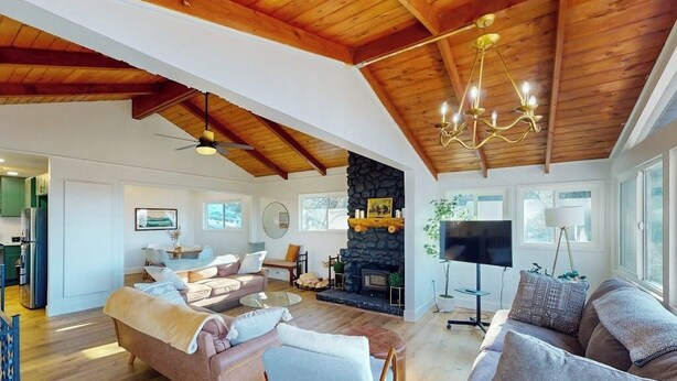 A spacious living area with a stone fireplace, wooden ceiling beams, and a television.