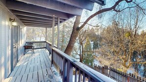 A wooden deck with a railing, a chair, and a table.