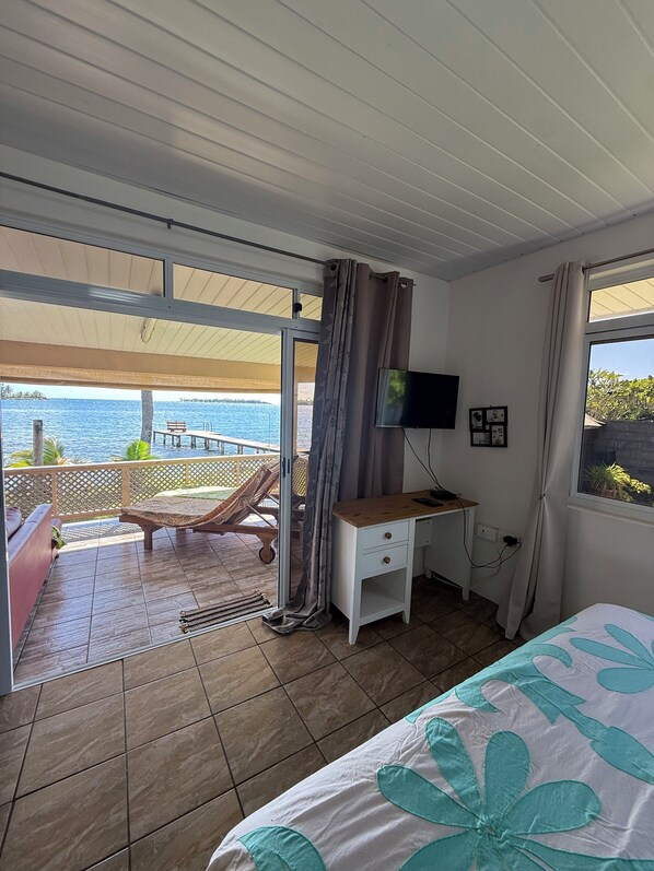 A room with a bed, a desk, a TV, and a view of the sea. - Fare Holidays Raiatea (Avera, Raiatea)
