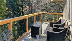 Een houten terras met een reling, buitenmeubilair en een barbecue.