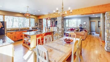 A spacious kitchen with a large island, wooden flooring, and a stone fireplace.