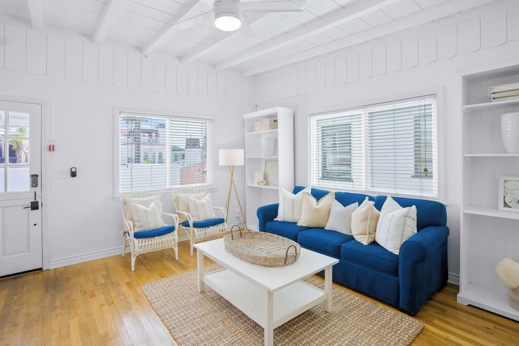Ein Wohnzimmer mit blauem Sofa, weißen Wänden und Holzböden.