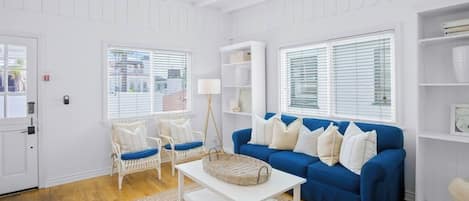 Ein Wohnzimmer mit blauem Sofa, weißen Wänden und Holzböden.