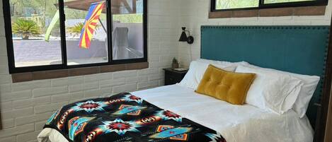 A bedroom with a bed, a window with a view, a nightstand, and a headboard.